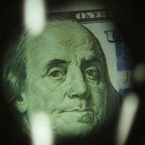 $100 dollar bill under a magnifying Glass