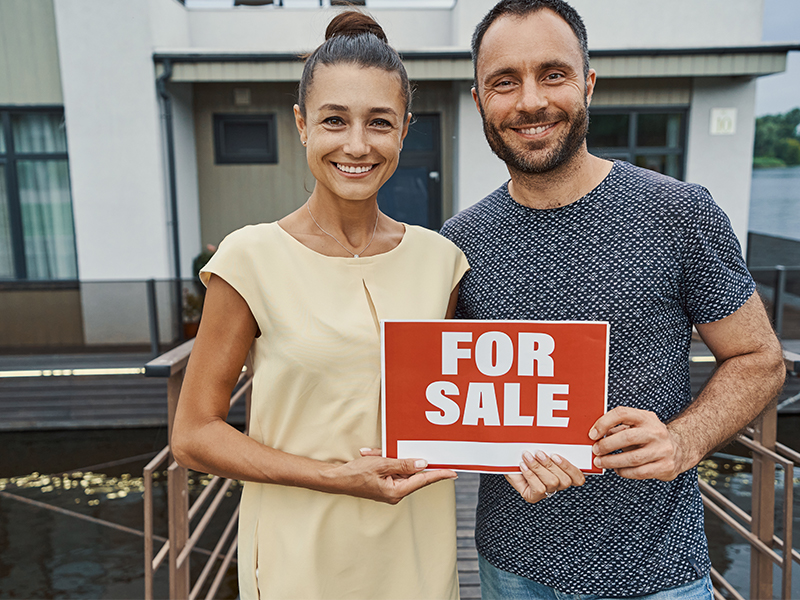 Two People Hold A For Sale Sign